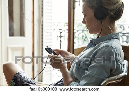 Stock Photo - Woman listening to music playing on smartphone. Fotosearch