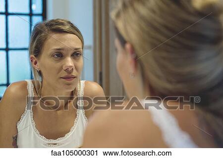 Woman looking at self in bathroom mirror View Large Photo Image Stock Image - Woman looking at self in bathroom mirror. Fotosearch