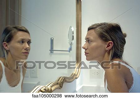 Woman looking at self in bathroom mirror View Large Photo Image Stock Photo - Woman looking at self in bathroom mirror. Fotosearch