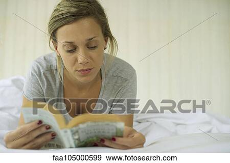 Woman lying on stomach reading book View Large Photo Image Stock Photo - Woman lying on stomach reading book. Fotosearch