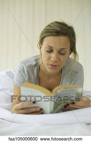 Stock Image - Woman reading in bed. Fotosearch