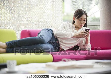Stock Photograph - Woman relaxing at home with smartphone. Fotosearch