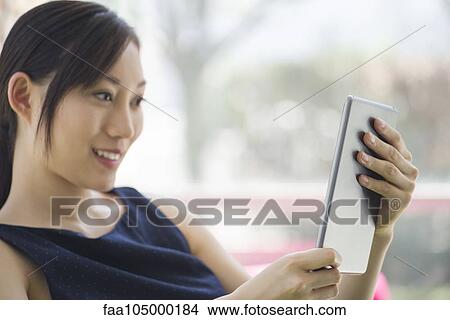 Woman relaxing with digital tablet View Large Photo Image Picture - Woman relaxing with digital tablet. Fotosearch