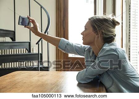 Woman taking selfie with smartphone View Large Photo Image Stock Image - Woman taking selfie with smartphone. Fotosearch