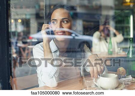 Woman talking on cell phone in coffee shop View Large Photo Image Stock Image - Woman talking on cell phone in coffee shop. Fotosearch