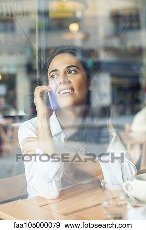 Woman talking on cell phone in coffee shop View Large Photo Image Stock Photo - Woman talking on cell phone in coffee shop. Fotosearch