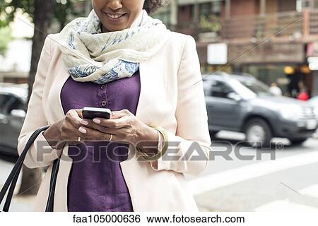 Stock Photograph - Woman text messaging on street. Fotosearch