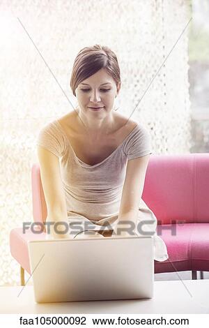 Stock Image - Woman using laptop computer at home. Fotosearch