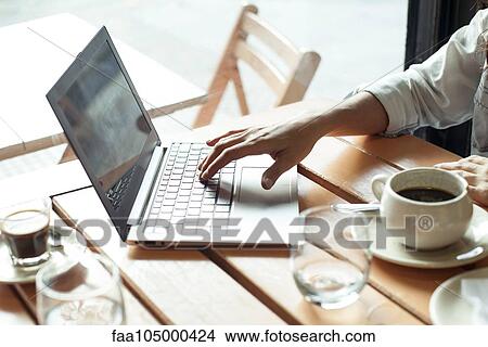 Picture - Woman using laptop computer in coffee shop. Fotosearch