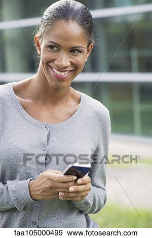 Woman using smartphone and smiling outdoors View Large Photo Image Stock Photo - Woman using smartphone and smiling outdoors. Fotosearch