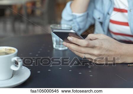 Stock Photography - Woman using smartphone at cafe, cropped. Fotosearch