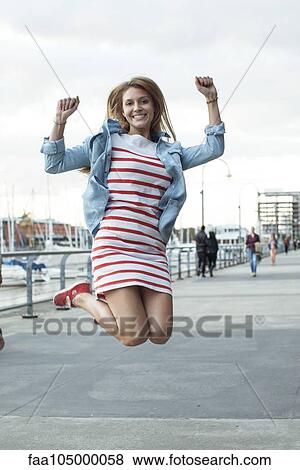 Stock Photo - Young woman jumping for joy outdoors. Fotosearch