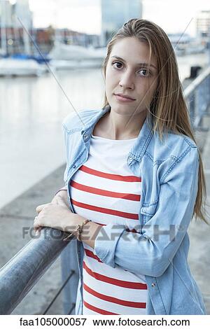 Stock Photo - Young woman leaning against railing, portrait. Fotosearch