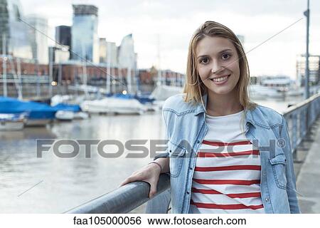 Young woman leaning against railing, smiling, portrait View Large Photo Image Stock Photograph - Young woman leaning against railing, smiling, portrait. Fotosearch