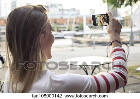 Young woman posing for a selfie at outdoor cafe View Large Photo Image Stock Image - Young woman posing for a selfie at outdoor cafe. Fotosearch