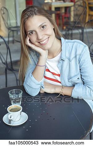 Stock Image - Young woman relaxing at cafe, portrait. Fotosearch