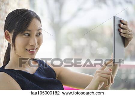 Young woman using a digital tablet to take a selfie View Large Photo Image Stock Image - Young woman using a digital tablet to take a selfie. Fotosearch