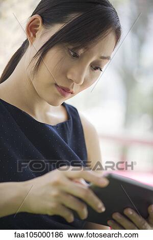 Young woman using digital tablet View Large Photo Image Stock Photograph - Young woman using digital tablet. Fotosearch