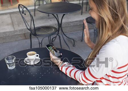 Young woman using smartphone to video chat in cafe View Large Photo Image Stock Photo - Young woman using smartphone to video chat in cafe. Fotosearch