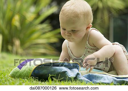 Stock Photograph - Baby sitting on blanket outdoors. Fotosearch