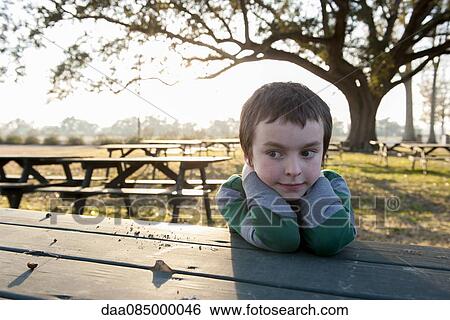 Boy sitting at picnic table in park, portrait View Large Photo Image Stock Photograph - Boy sitting at picnic table in park, portrait. Fotosearch