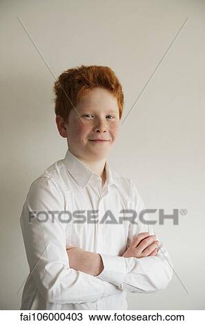 Stock Image - Boy smiling confidently with arms folded, portrait. Fotosearch