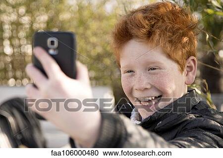 Stock Image - Boy using smartphone to take a selfie. Fotosearch