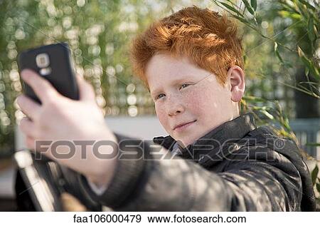 Boy using smartphone to take a selfie View Large Photo Image Stock Photo - Boy using smartphone to take a selfie. Fotosearch