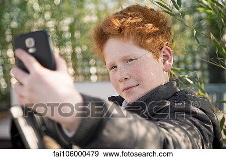 Stock Photo - Boy using smartphone to take a selfie. Fotosearch