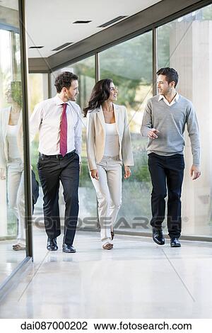 Stock Image - Business team members brainstorming while on the move. Fotosearch