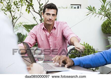 Businessman at meeting with colleagues View Large Photo Image Stock Photo - Businessman at meeting with colleagues. Fotosearch