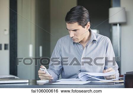 Stock Photograph - Businessman checking smartphone in office. Fotosearch