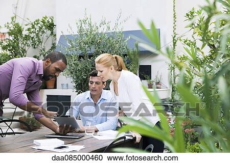 Businessman presenting ideas displayed on digital tablet to colleagues View Large Photo Image Stock Image - Businessman presenting ideas displayed on digital tablet to colleagues. Fotosearch