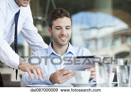 Businessman showing colleague how to use digital tablet View Large Photo Image Stock Photo - Businessman showing colleague how to use digital tablet. Fotosearch