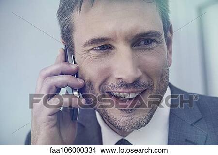 Picture - Businessman talking on cell phone, smiling cheerfully. Fotosearch