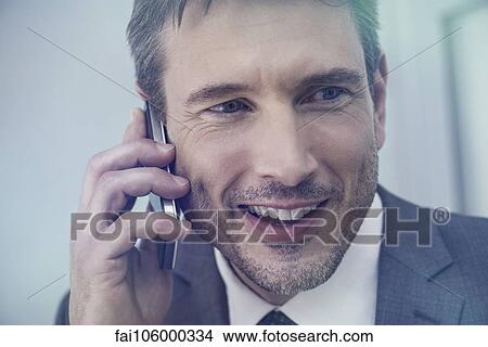 Businessman talking on cell phone, smiling cheerfully View Large Photo Image Picture - Businessman talking on cell phone, smiling cheerfully. Fotosearch