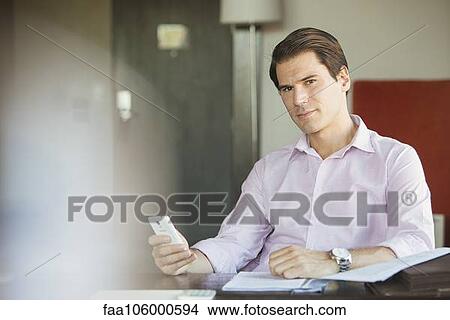 Businessman using smartphone at desk, portrait View Large Photo Image Picture - Businessman using smartphone at desk, portrait. Fotosearch