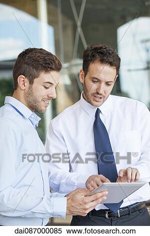 Businessmen collaborating using digital tablet View Large Photo Image Stock Photography - Businessmen collaborating using digital tablet. Fotosearch