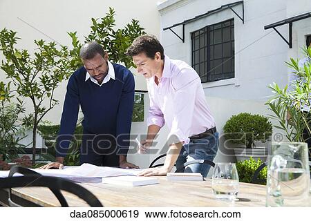 Stock Photo - Businessmen discussing blueprint. Fotosearch