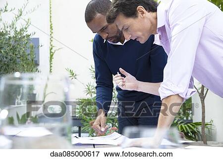 Stock Photo - Businessmen discussing documents. Fotosearch