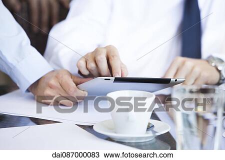 Businessmen discussing work using digital tablet over coffee View Large Photo Image Stock Image - Businessmen discussing work using digital tablet over coffee. Fotosearch