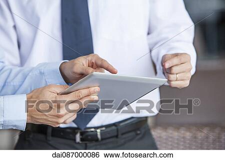 Stock Photograph - Businessmen using digital tablet. Fotosearch