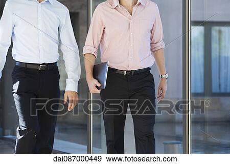 Stock Photo - Businessmen walking in office corridor. Fotosearch