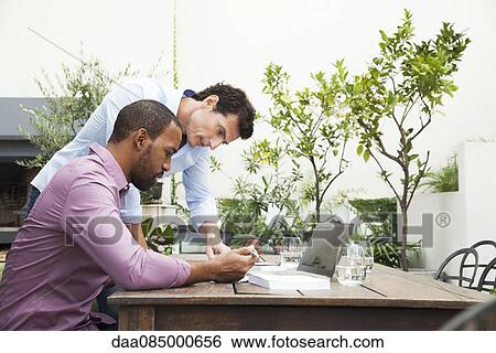 Stock Photograph - Businessmen working closely together on project. Fotosearch