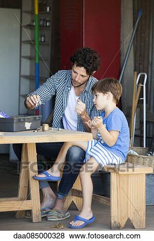 Child helping his father sort work materials View Large Photo Image Stock Photo - Child helping his father sort work materials. Fotosearch