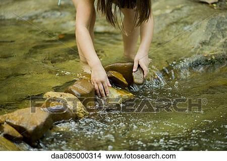 Child using rocks to build a dam in a shallow stream View Large Photo Image Picture - Child using rocks to build a dam in a shallow stream. Fotosearch
