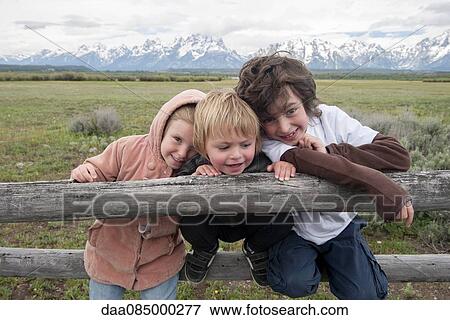Stock Photo - Children leaning against fence in Grand Teton National Park, Wyoming, USA. Fotosearch