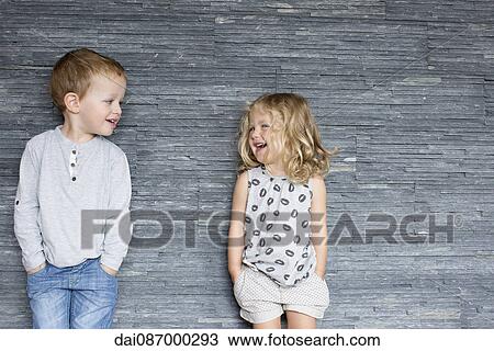 Children leaning against wall, smiling at each other View Large Photo Image Stock Image - Children leaning against wall, smiling at each other. Fotosearch