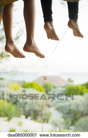 Stock Photo - Children sitting side by side with bare feet dangling. Fotosearch