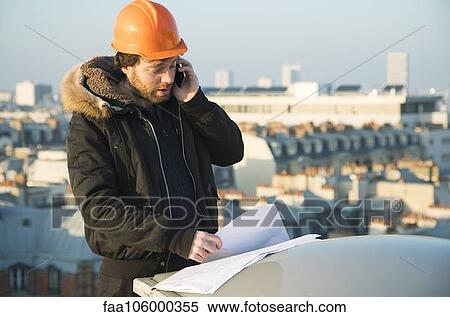 Construction supervisor studying blueprints and talking on cell phone View Large Photo Image Stock Photography - Construction supervisor studying blueprints and talking on cell phone. Fotosearch